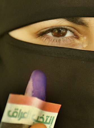 With tears rolling down her eyes, a veiled Iraqi woman shows off her finger stained with blue ink and a small card reading 'Elect Iraq' after she cast her vote in a polling station in Amman, January 30, 2005. REUTERS/Ali Jarekji