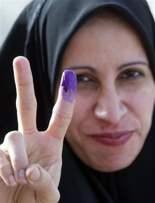 An Iraqi woman holds up her hand, and shows a purple finger, indicating she has just voted, as she leaves a polling station in the centre of Az Zubayr, southern Iraq, Sunday, Jan. 30, 2005.(AP Photo/Andrew Parsons/Pool)